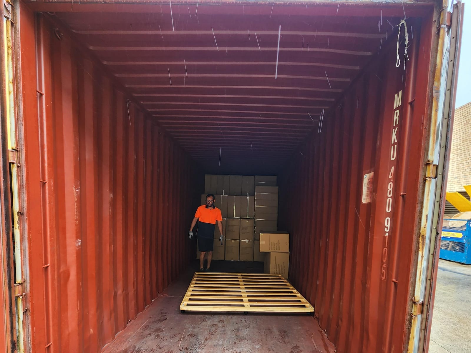 Calima worker hand-unloading a floor-loaded shipping container