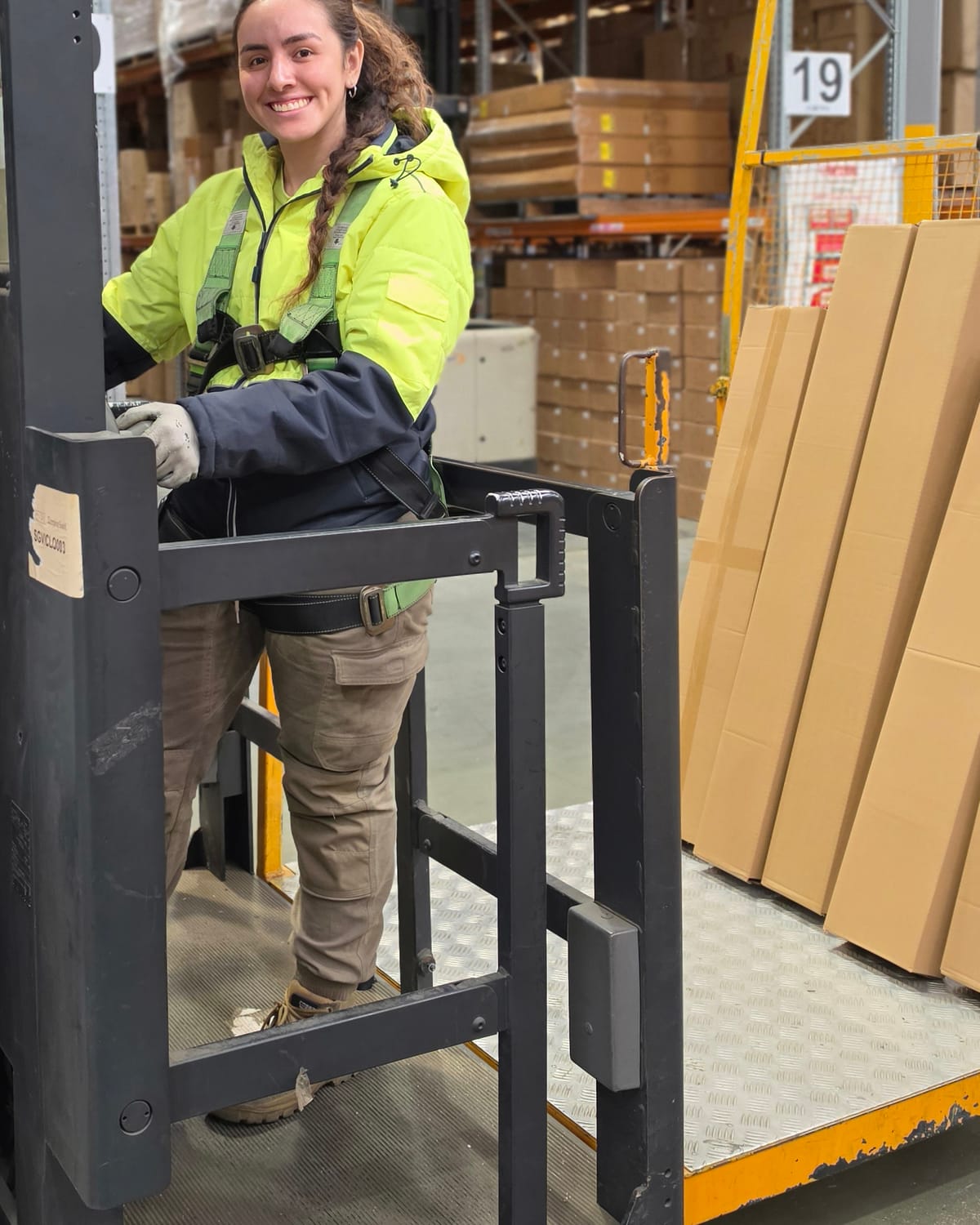 Smiling Calima operator in the cage of an order picker in a warehouse