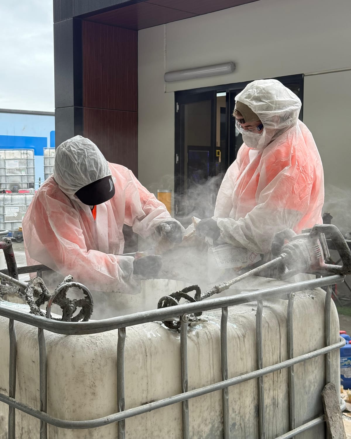 Two workers in full protective equipment on an industrial site