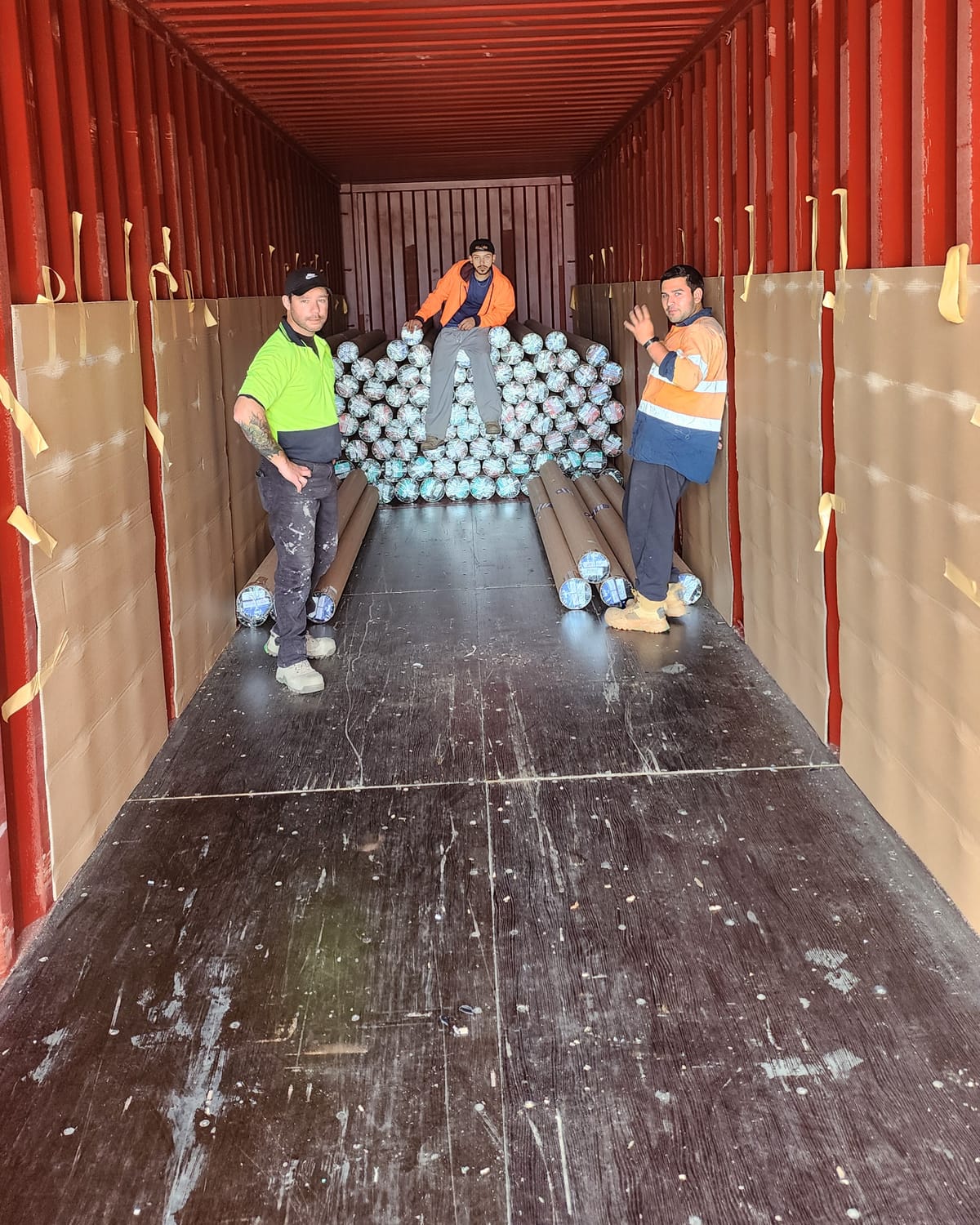 Three Calima workers inside a shipping container, one waving at the camera